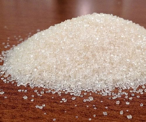 Pile of pale sugar crystals on a wooden surface