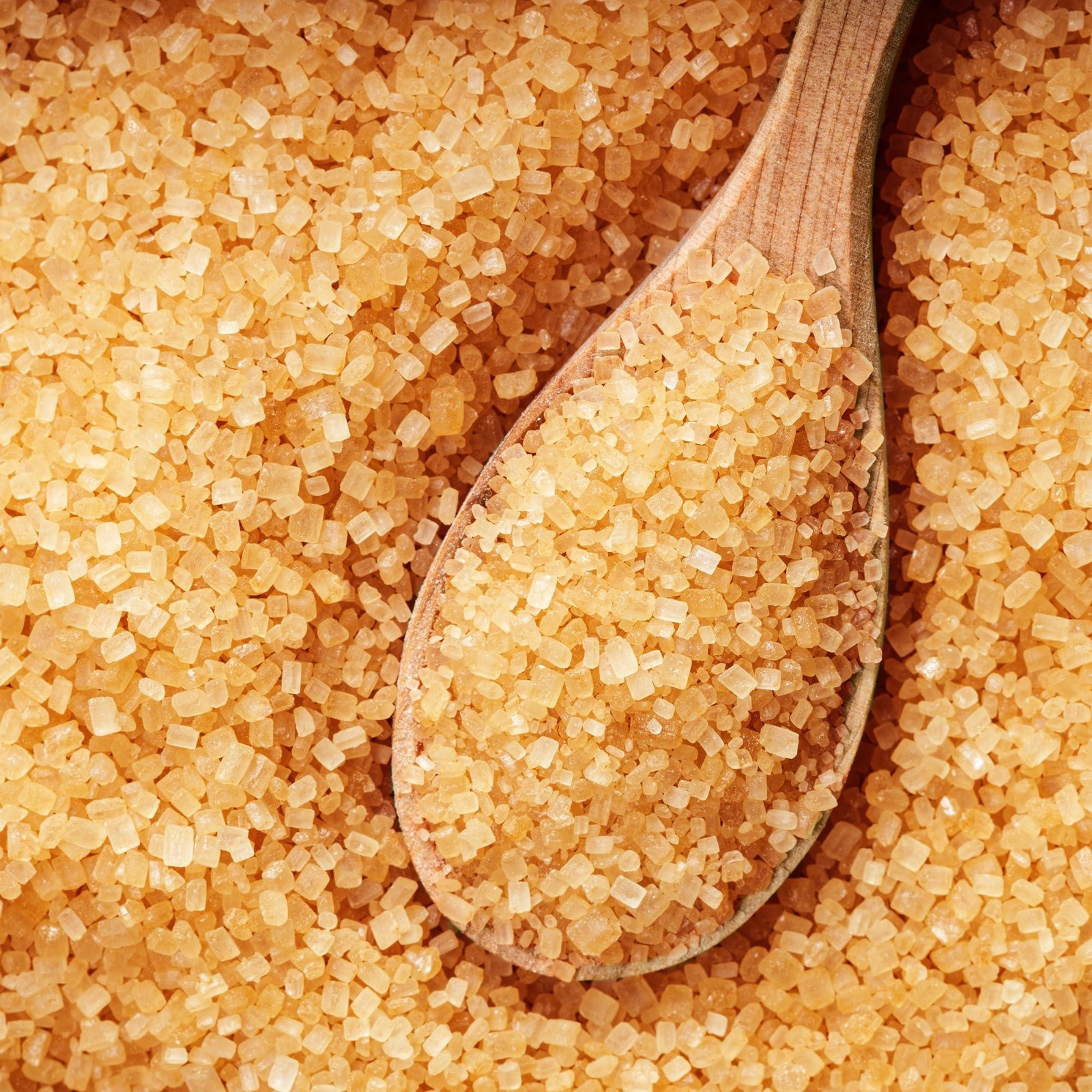 Cristais dourados de açúcar bruto com colher de madeira